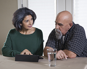 Man and woman sitting at table looking at electronic tablet.