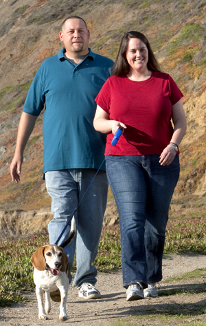 Hombre y mujer caminando al aire libre con un perro.