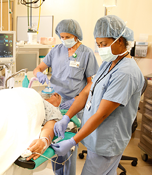 Proveedoras de atención médica en un quirófano preparando a un hombre para la cirugía.