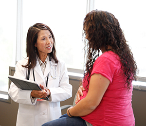 Embarazada en un consultorio hablando con una proveedora de atención médica.