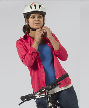 Una adolescente en bicicleta colocándose el casco.